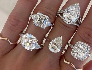 Hand adorned with five large diamond rings in various cuts.