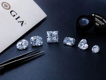 Various diamond cuts displayed with a GIA certificate and jeweler's tools.