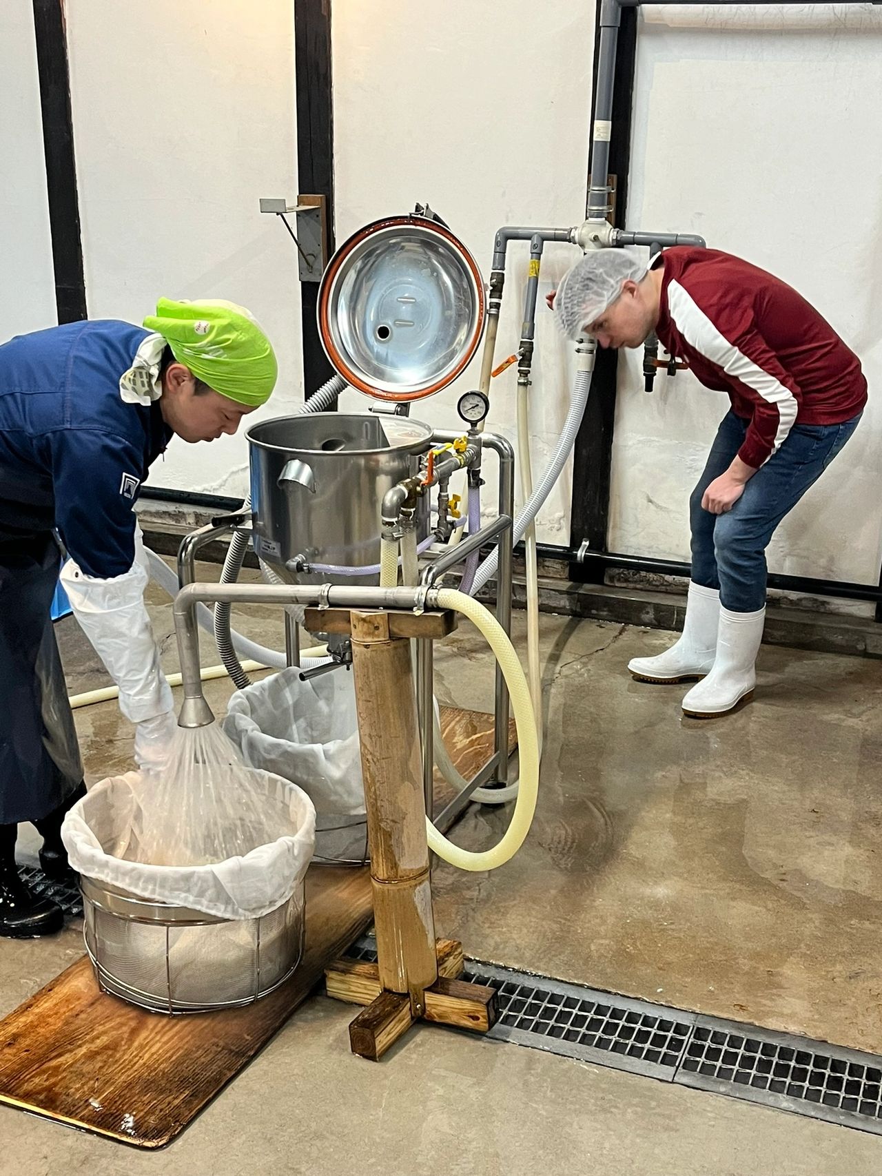 Two people operating a rice washing machine and washing rice for making Japanese sake