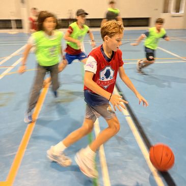 Boy playing basketball indoors with friends.