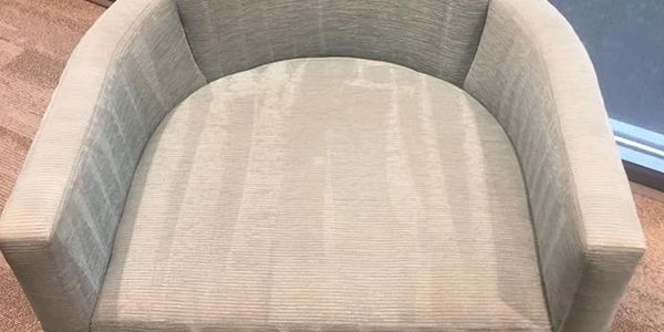 Beige upholstered armchair with wooden legs on carpet.