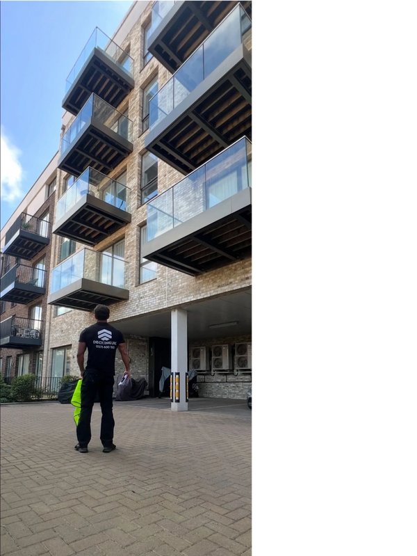 Man in a black shirt stands in front of a modern building with glass balconies.