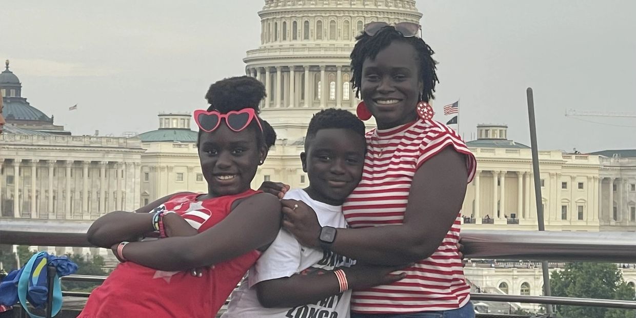 Three smiling individuals posing in front of the U.S. Capitol.
