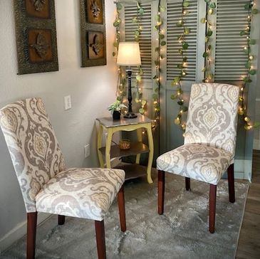 Two patterned chairs with a side table and lamp in a cozy, decorated corner.