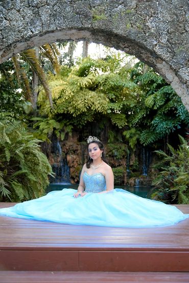 Young woman in a blue ball gown and tiara outdoors.