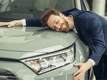 Car lover hugging his clean and shiny vehicle.