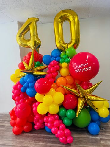 Large birthday balloon bouquet with number 40, starburst balloons, and jumbo Happy Birthday balloon.