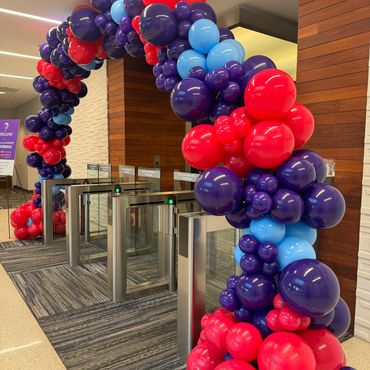 An organic arch in purple, pink, and blue draped over the entrance gates.