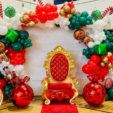 White backdrop with Christmas balloon garland and Santa chair
