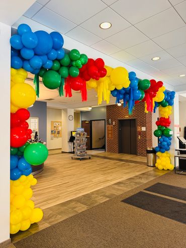 Colorful balloon arch with streamers for a public library summer celebration event.