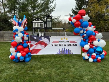 Corporate balloon décor featuring an organic balloon column and garland around the company banner.