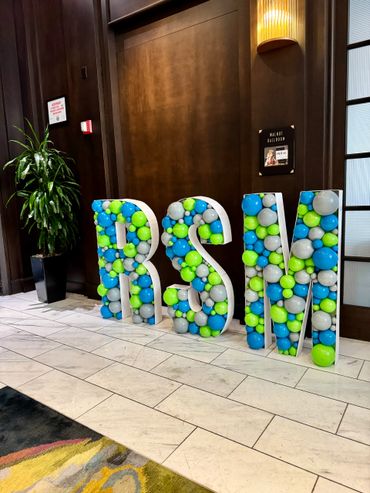 Mosaic marquee letters at a corporate event, filled with balloons in company logo colors.