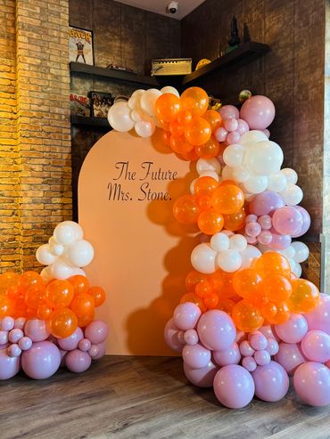 Colorful balloon arch around a peach backdrop for a bridal event.