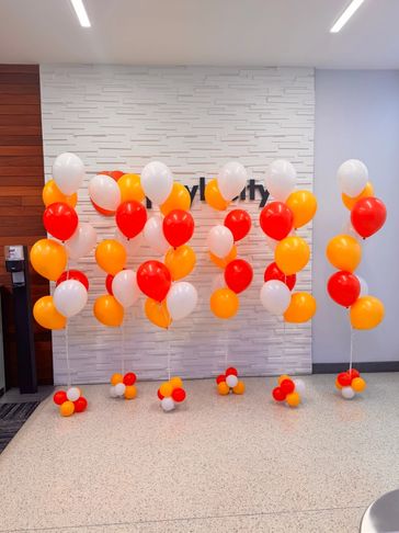 Six helium balloon bouquets with seven white, orange, and red balloon each.