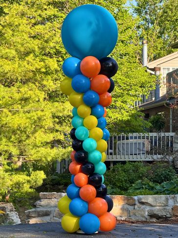 One tall Roman shaped balloon column in yellow, blue, orange, black, and green with a jumbo topper.