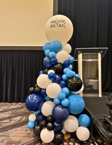 Organic triangle shape balloon column with large jumbo balloon toper and company logo. 