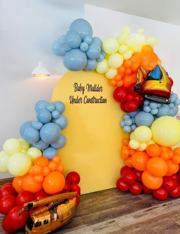 Yellow Arch wall with organic balloon garlands, in red, orange, yellow, and baby blue colors.