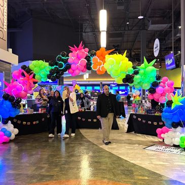 Neon balloon arch with people walking.