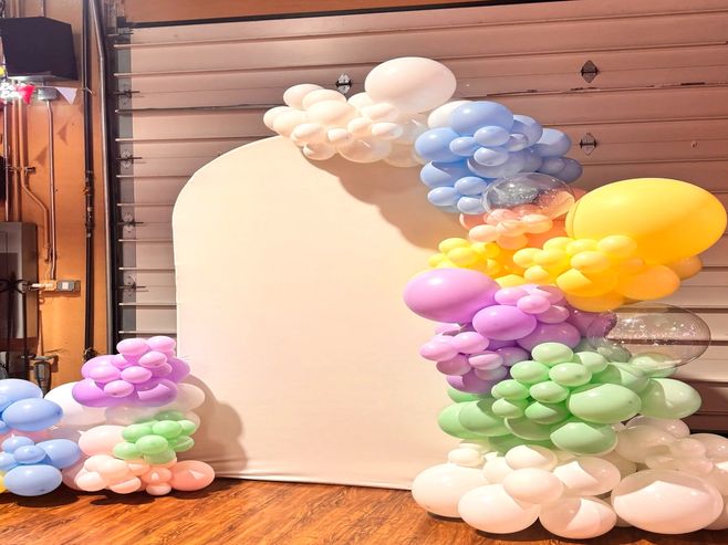 Pastel Easter balloon garland with bubble balloon accent on a white arch stand.