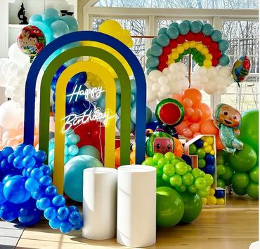 Cocomelon birthday décor with rainbow shaped arch, dessert tables and marquee number one.