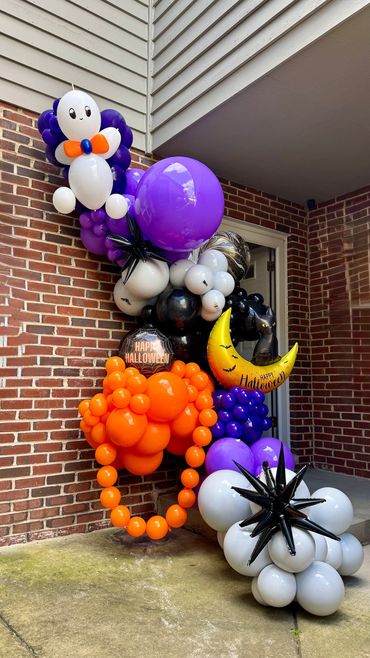 Halloween balloon garland with ghost, moon, kitten, and purple accent balloon by a front door.