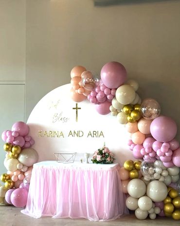 Round white backdrop with vinyl sign and organic balloon garland in grey pink, and gold for baptism.