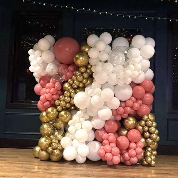 White, gold, and peach organic balloon wall installed in a restaurant.