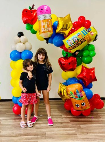Freestanding balloon garland with foil toppers like school bus, stars and crayons, exciting for kids