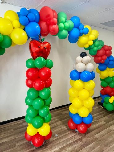 Balloon column shaped like a pencil, alongside a column topped with a cheerful apple in school color