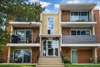 Three-story residential building with balconies and greenery.