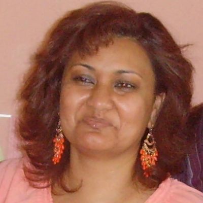 Woman with red hair and orange earrings smiling gently.