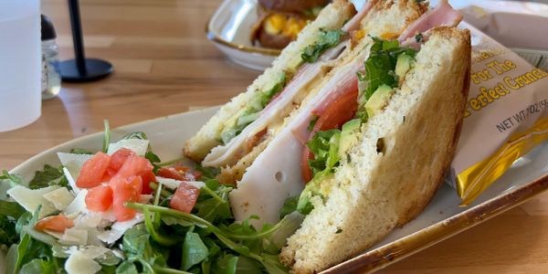 A fresh turkey sandwich with lettuce, tomato, and a side salad on a tray.