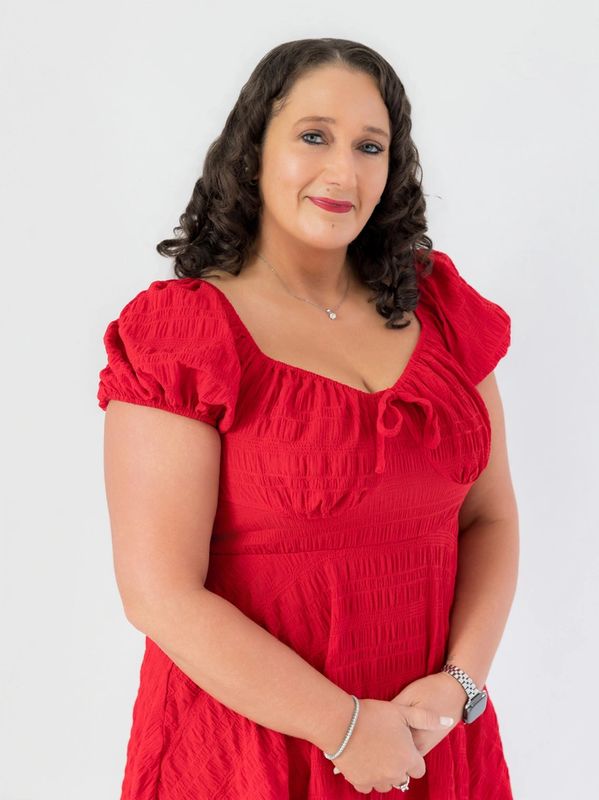 Woman in a red dress with curly hair smiling.