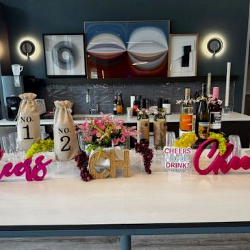 Decorative bar setup with bottles, flowers, and grapes.
