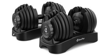 Adjustable Bowflex dumbbells with multiple weight plates on a sleek black stand.