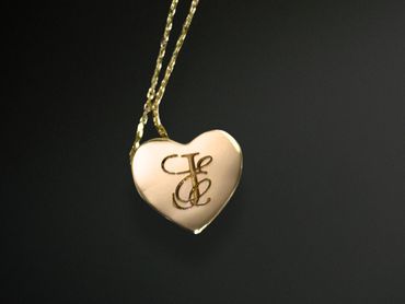 Heart-shaped gold pendant with initials on a chain.