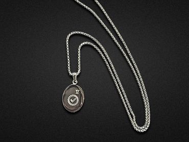 Silver necklace with an engraved oval pendant.