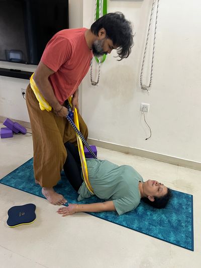 A man helping a woman stretch using a yoga strap.
