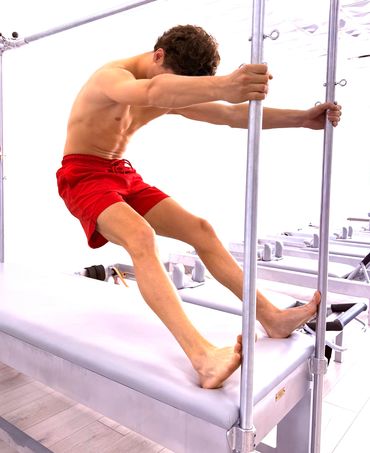 Man in red shorts stretching on exercise equipment.