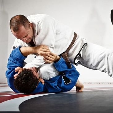 Grappler applying a choke from the knee on belly position in JiuJitsu class