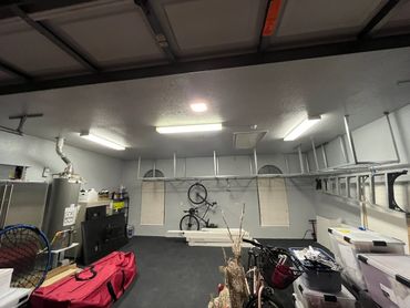 Organized garage with bicycles, storage bins, and ceiling-mounted racks.