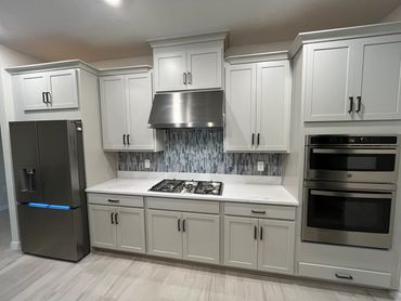 Modern kitchen with white cabinets, stainless steel appliances, and a tiled backsplash.