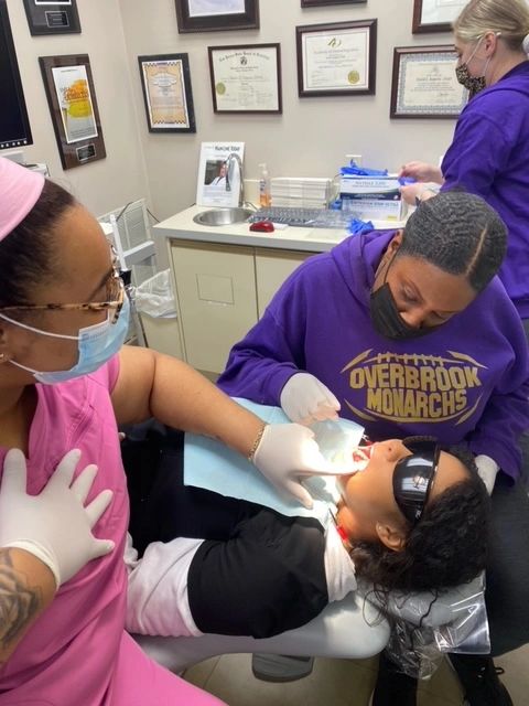 Students training to be dental assistants in  dental office. They are completing hands-on training.
