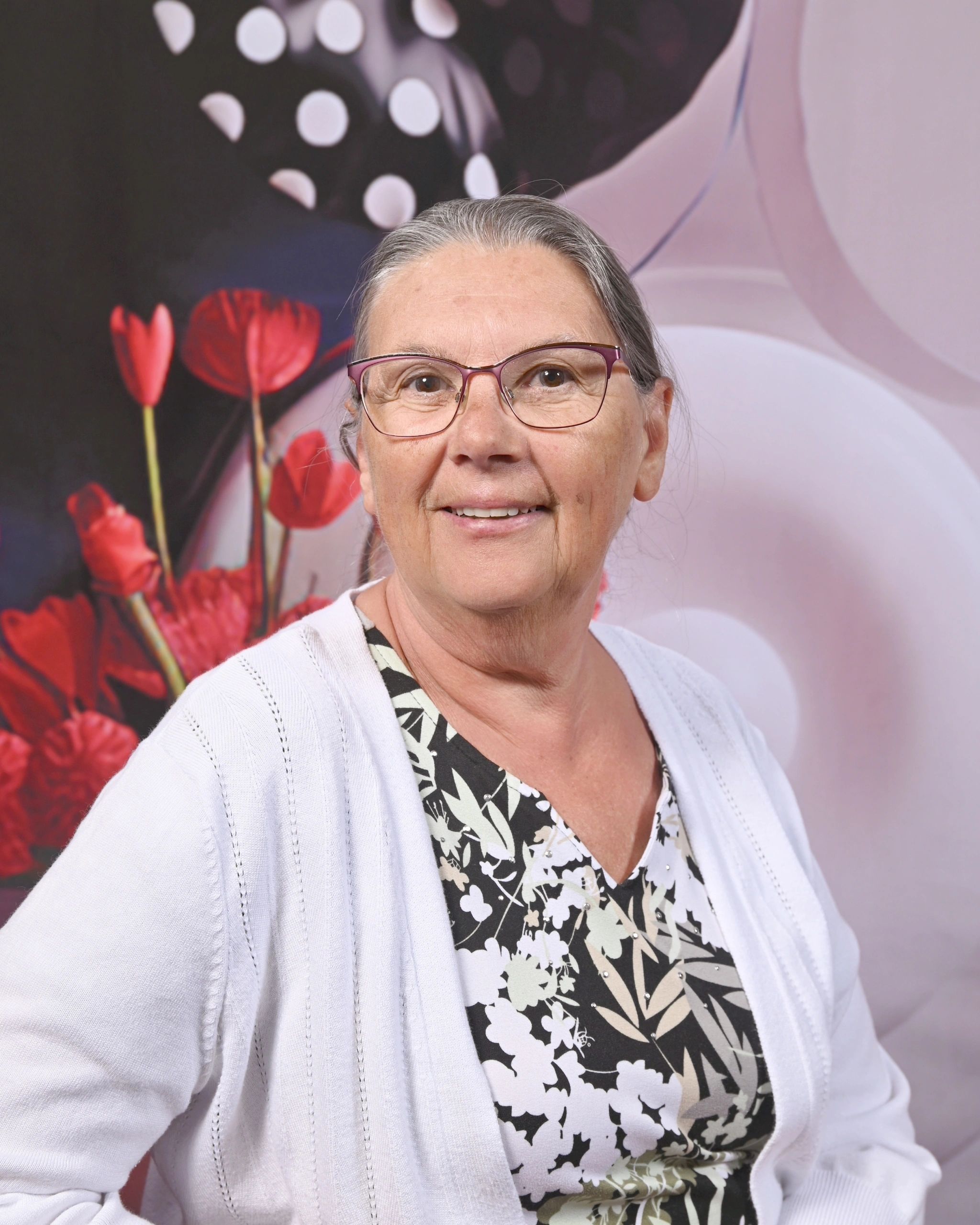 Smiling  woman with glasses in casual attire outdoors.