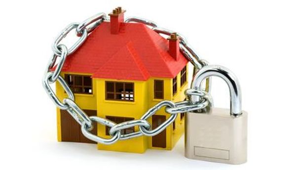 A toy house secured with a chain and padlock symbolizing home security.