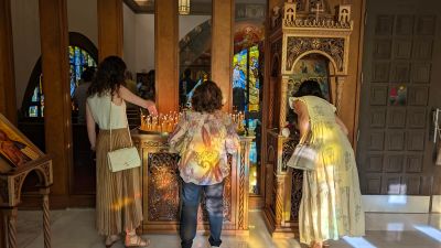 Three women lighting candles in a church.