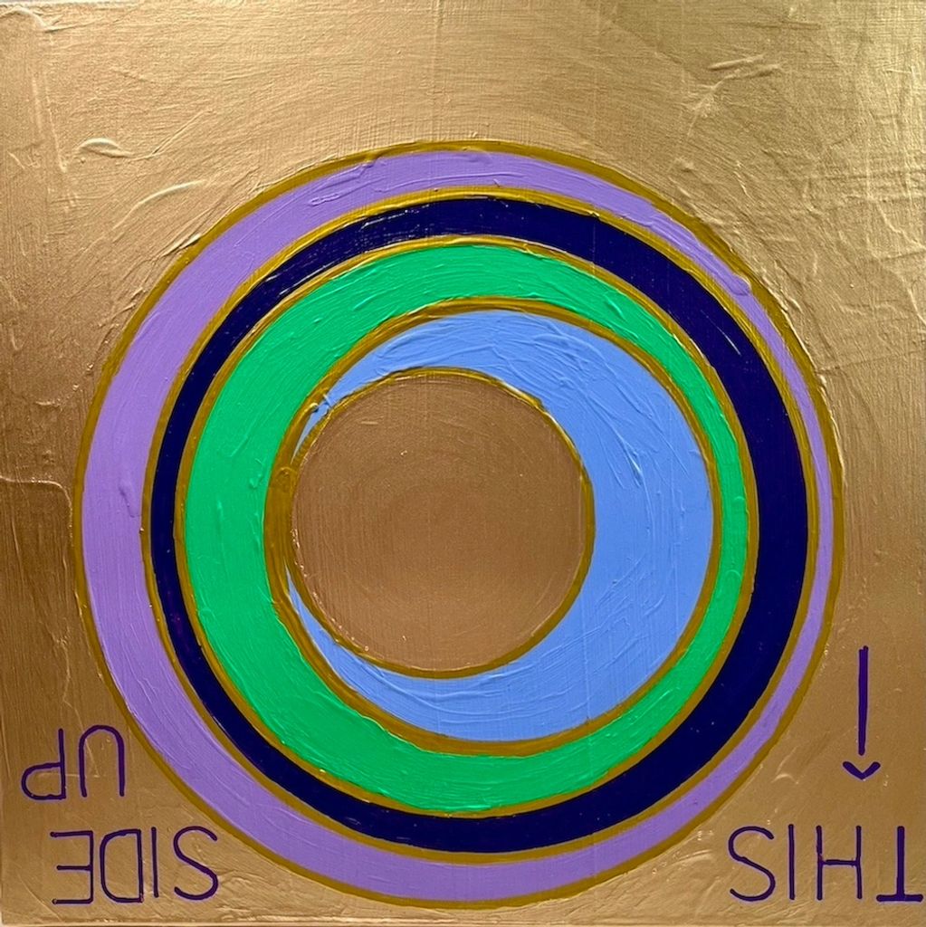 Colorful concentric circles on a gold textured background with upside-down text.