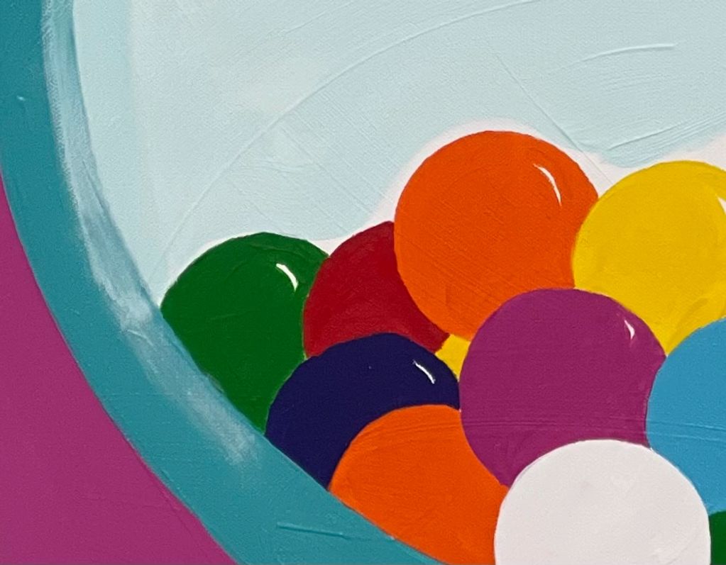 Close-up of colorful balls in a container with a teal rim and purple background.