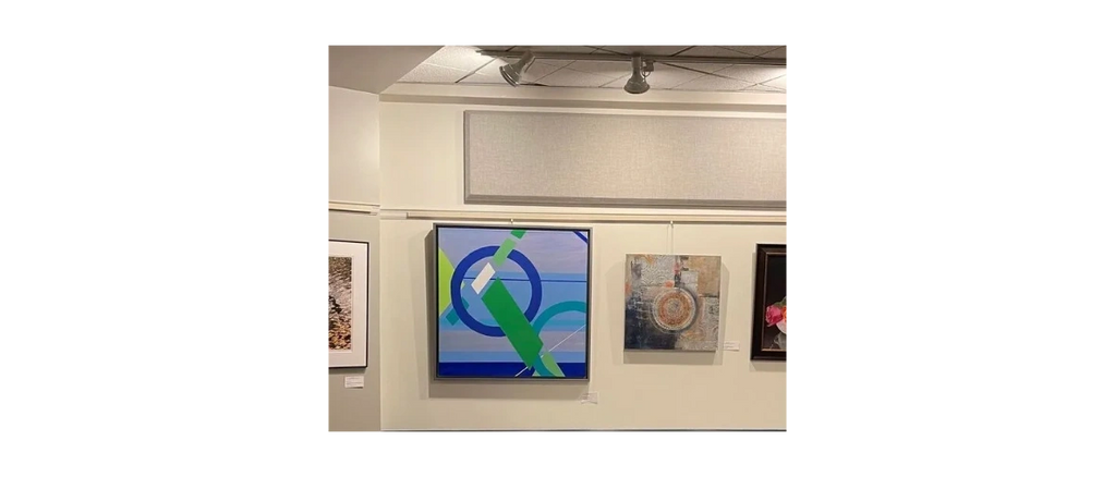 Abstract geometric paintings displayed in an art gallery with spotlighting.