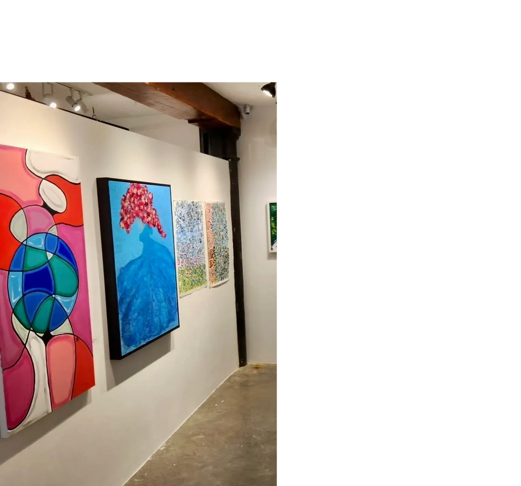 Art gallery wall with colorful abstract and floral paintings.